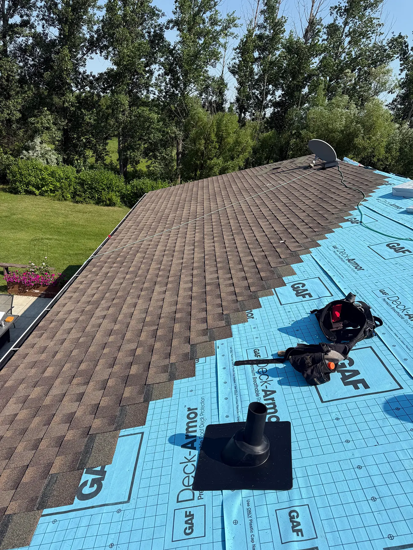 Roof replacement in progress after storm damage, with new asphalt shingles laid over GAF synthetic underlayment